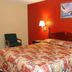 Executive Inn Rocky Top guest room with patterned bedspread, red accent wall, lamps and chair