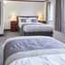 The Appleby Inn Hotel in Swadlincote guest room with two beds, bedside lamps, dresser and wall mirror