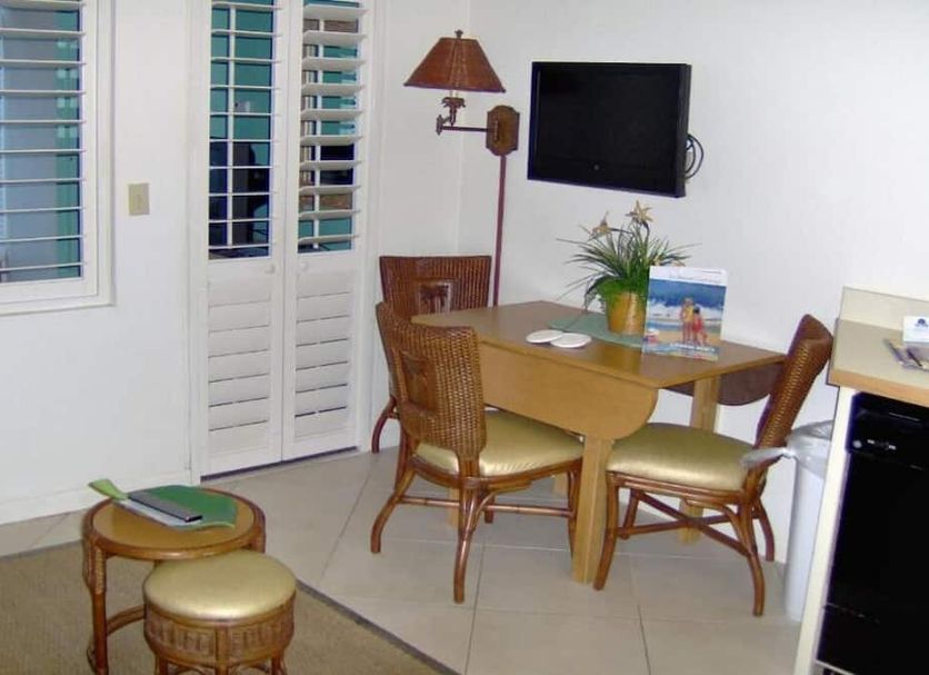 Islander Beach Resort New Smyrna Beach room with table, chairs, wall TV and plantation shutters