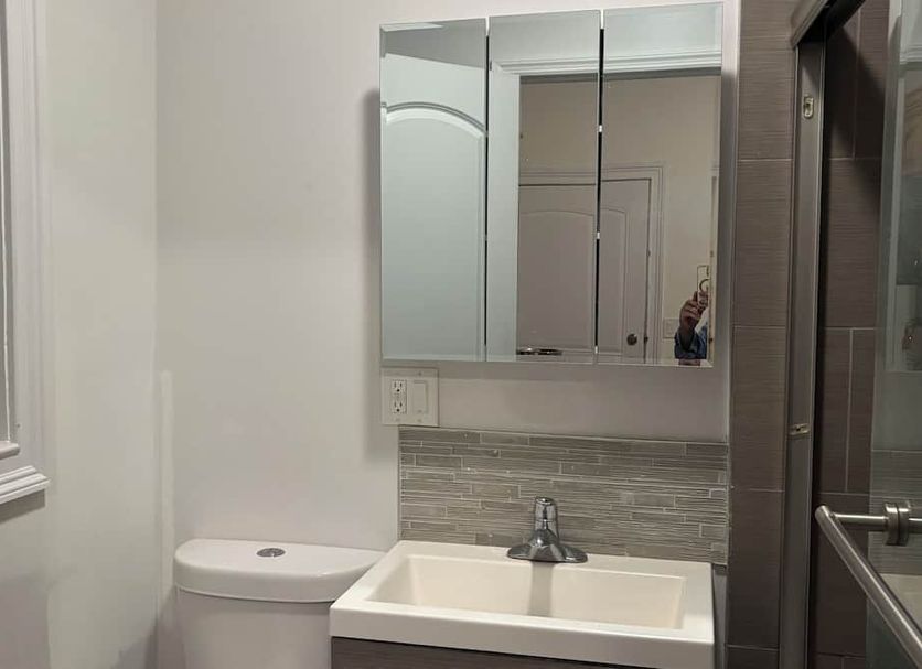 Motel Casa Penn in Newark bathroom with sink, toilet, mirrored cabinet, and tiled backsplash