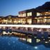 Cayo Exclusive Resort & Spa in Elounda with illuminated infinity pool and mountain backdrop at dusk
