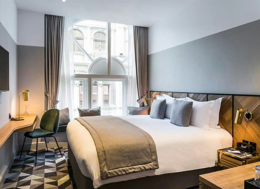 Victory House London hotel room with king bed, desk, and tall windows in London