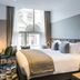 Victory House London hotel room with king bed, desk, and tall windows in London
