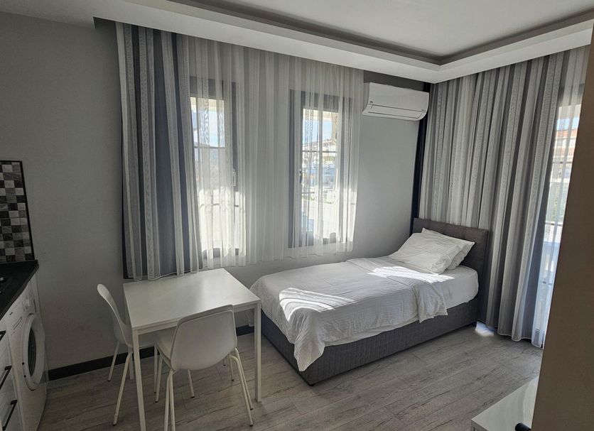 Cicek Apart Hotel Cesme room with single bed, dining table, curtains, and air conditioner