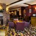 Premier Inn Ipswich South East lounge with brick fireplace, round tables, and purple chairs in Ipswich