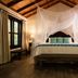 Hotel Jungle Lodge Tikal bedroom with canopy bed, mosquito net, wood-beam ceiling and bedside lamps