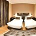 Velmore Hotel & Spa in Pretoria: twin beds, dark curtains, and a leather bench in a guest room.