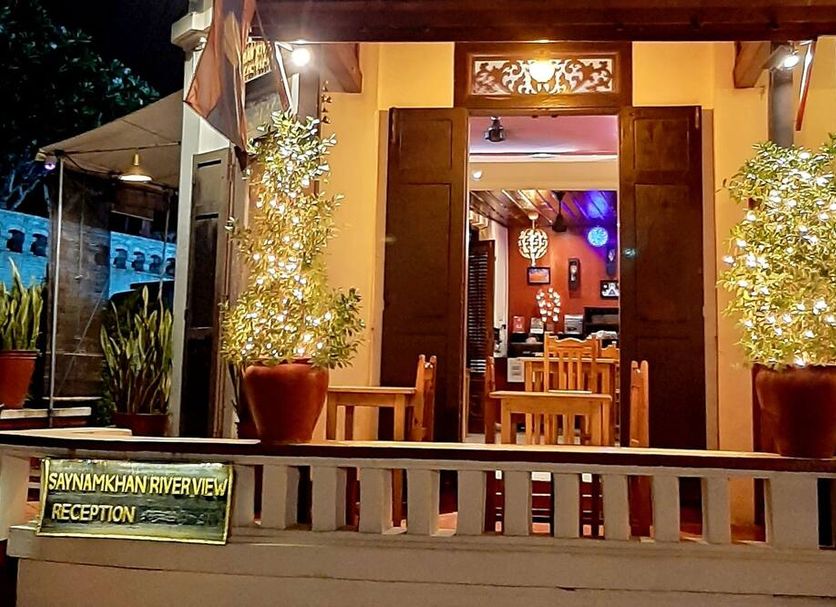 Saynamkhan River View reception entrance in Luang Prabang with potted trees and wooden seating