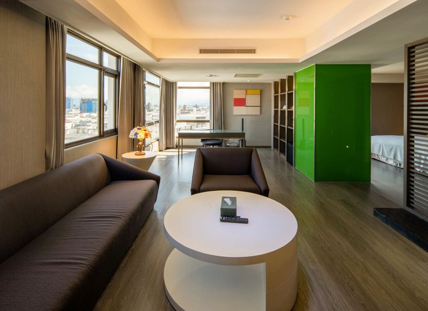Check Inn Select Hualien Linsen guest room with sofa, round coffee table, city view, and green accent wall