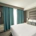 Sandman Signature Ottawa Airport Hotel guest room with king bed, teal curtains and bedside lamps in Ottawa