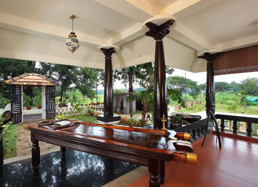 Achayans Homestay Mararikulam in Alappuzha: covered terrace with carved wooden table and garden view