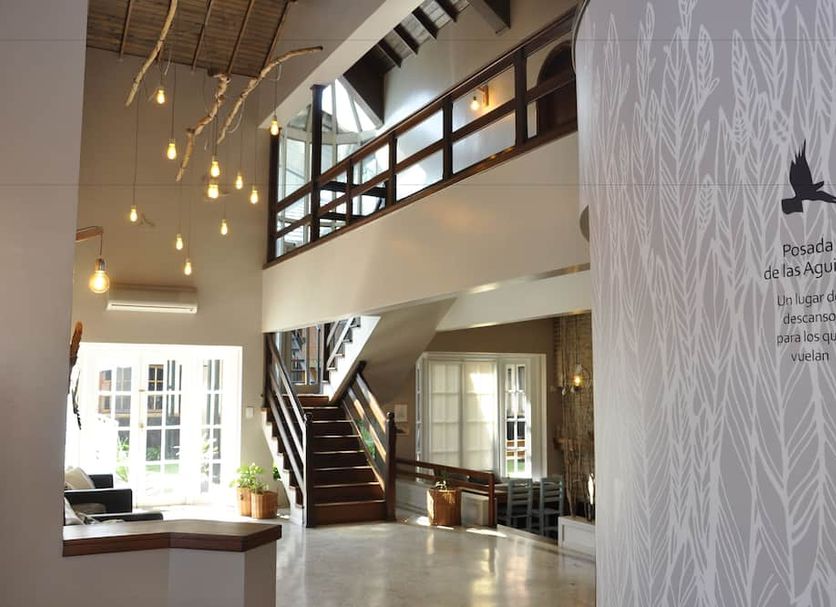Posada de las Aguilas Hotel Boutique in Ezeiza lobby with staircase, high ceiling, and hanging lights