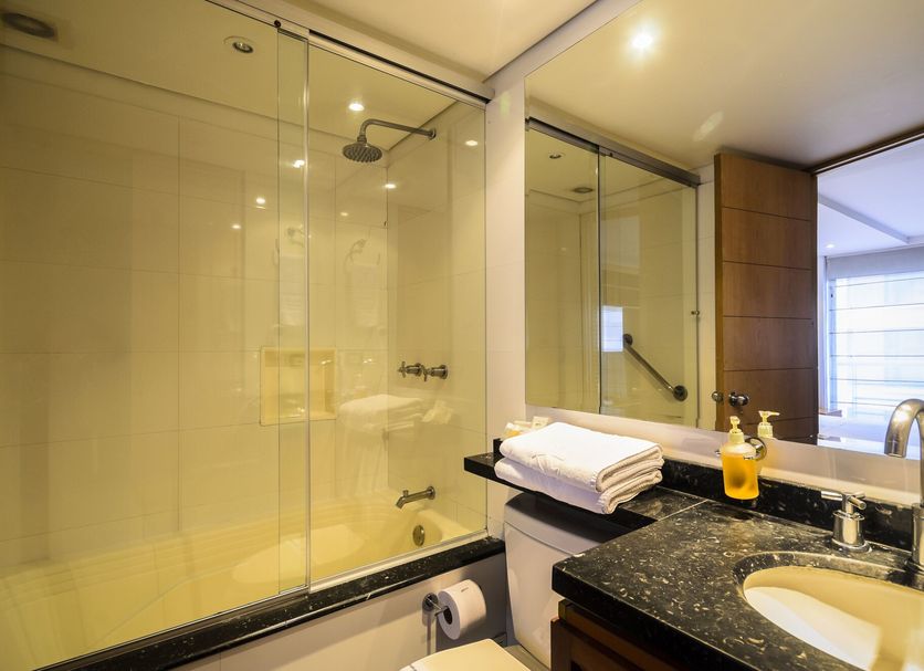 Travelers Obelisco Apartamentos bathroom in Bogotá with glass shower enclosure, sink and mirror