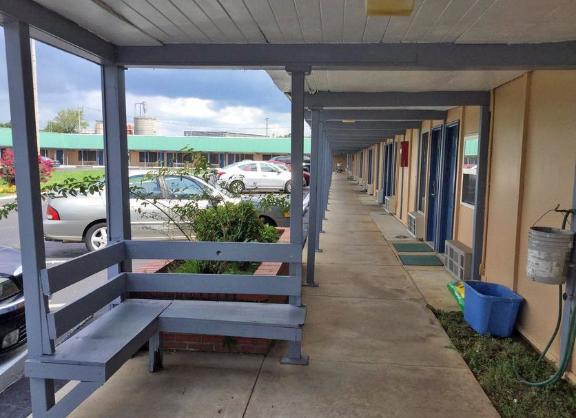 Scottish Inns Mcminnville exterior walkway with covered corridor, bench seating, and parking view
