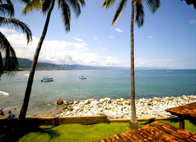 Villas del Sol en Los Tules, Puerto Vallarta: oceanfront view with palms, rocky shore and boats