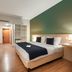 Pestana Curitiba guest room with double bed, wood floors, desk, shelves and green accent wall