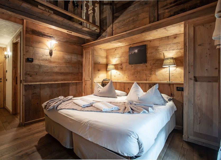 Hotel Chalet Svizzero in Courmayeur: cozy rustic bedroom with double bed and warm wood-paneled walls