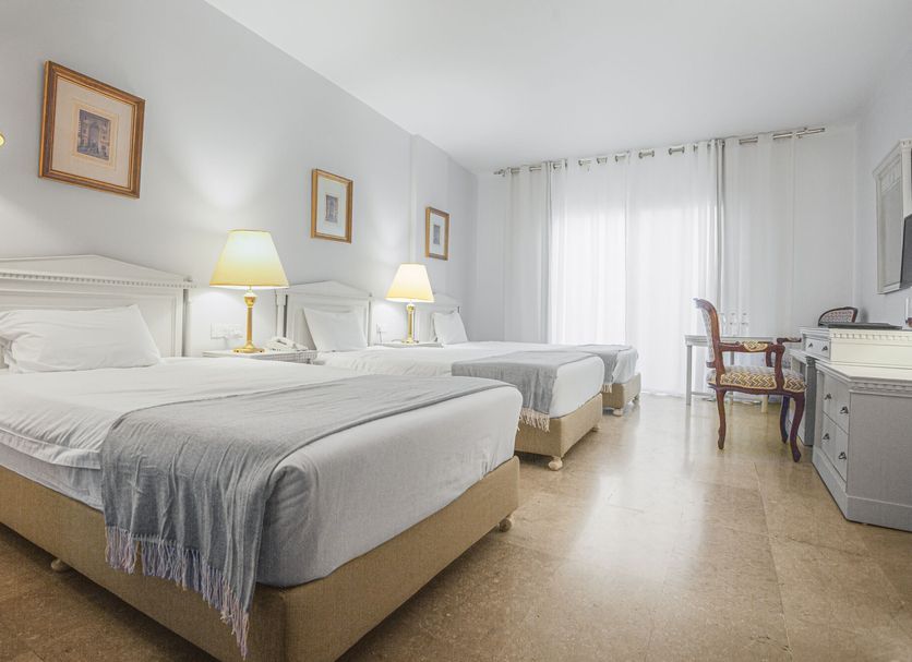 Grand Hotel Madaba in Madaba: bright twin guest room with bedside lamps, desk, and sheer-curtained window
