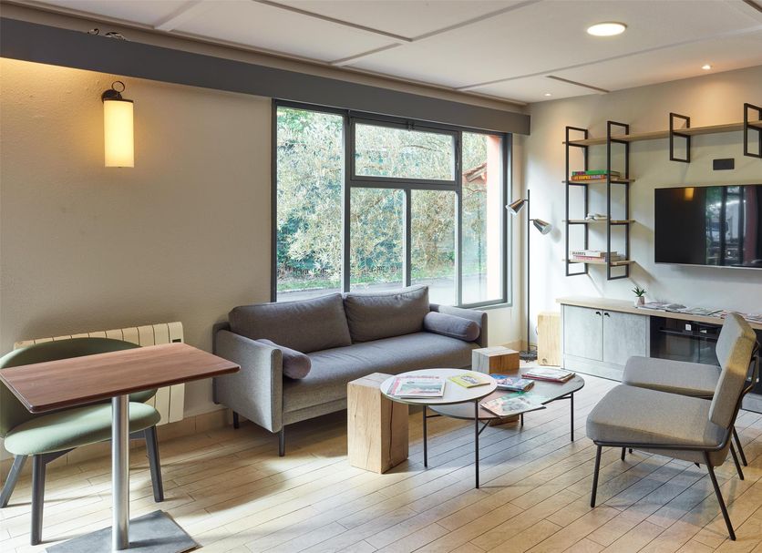 Campanile Nature - Sannois Ermont lounge in Sannois with sofa, chairs, TV, and large window