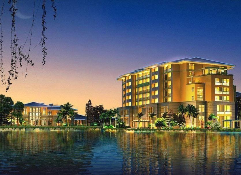 New Century Grand Hotel Kaifeng in Kaifeng at sunset beside a reflective lake
