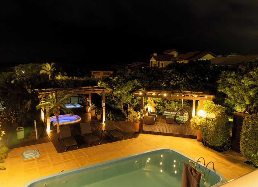 Pousada Ilha Faceira in Florianopolis with a lit outdoor pool and lounge area at night