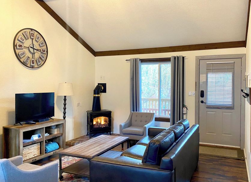 Bramblebank Cottages in Harrison Hot Springs, cozy living room with fireplace, sofa, TV, and window