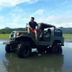 Bognot Lodge Mt Pinatubo Guesthouse in San Jose with a man sitting on an off-road jeep in shallow water