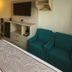 Floral Park Motor Lodge room in Queens with two beds, TV, and teal armchair