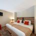 Aparthotel Adagio Lyon Patio Confluence room in Lyon with twin beds, wall-mounted TV, and red accent ottoman