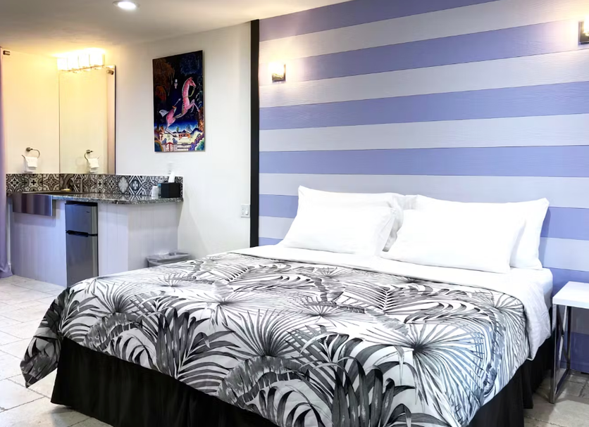 Retreat At Crystal Manatee room in Crystal River with striped accent wall and tropical-patterned bedspread