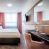 Home Hotel Dortmund guest room with double bed, desk, wall-mounted TV and window with pink curtains