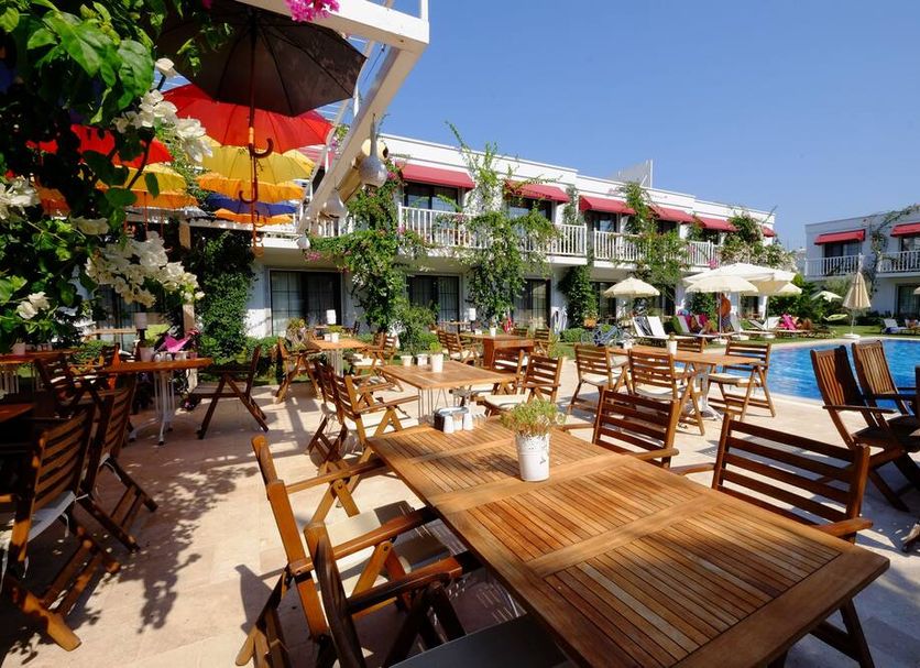 Villa Rustica Hotel in Gündoğan with poolside terrace, wooden tables, umbrellas and garden seating
