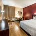 Red Roof Plus Long Island - Garden City guest room in Westbury with king bed, desk, and wall-mounted TV