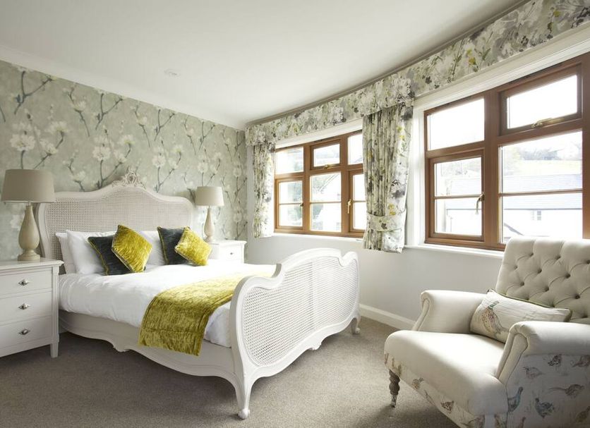 Exmoor White Horse Inn guest room in Minehead with floral wallpaper, white bed, and armchair