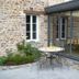 La Ferme de la Gronde in Bayeux: stone courtyard patio with bistro table and chairs beside glass doors