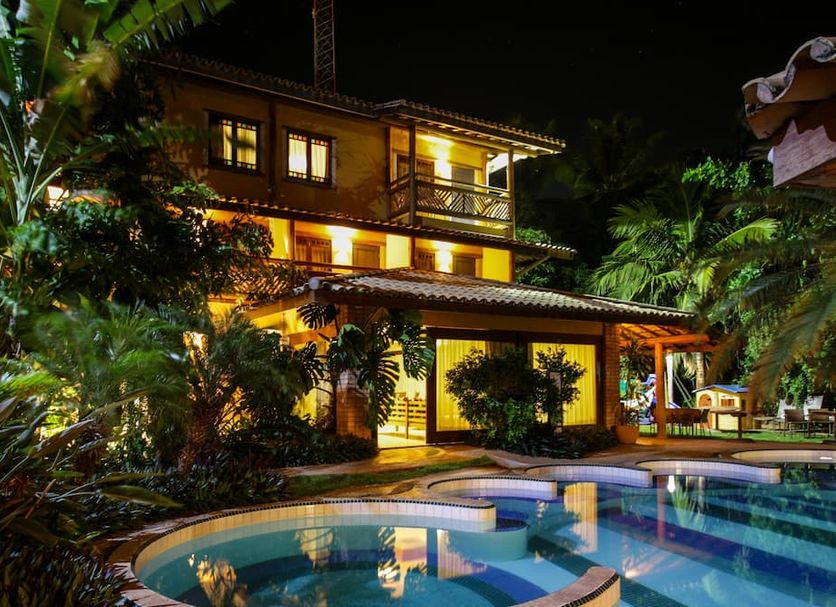 Night view of Hotel Via dos Corais in Mata de São João with illuminated pool and tropical gardens