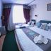 Rohat Hotel, Dushanbe: twin bedroom with patterned bedspread, curtains, wall sconces and window light