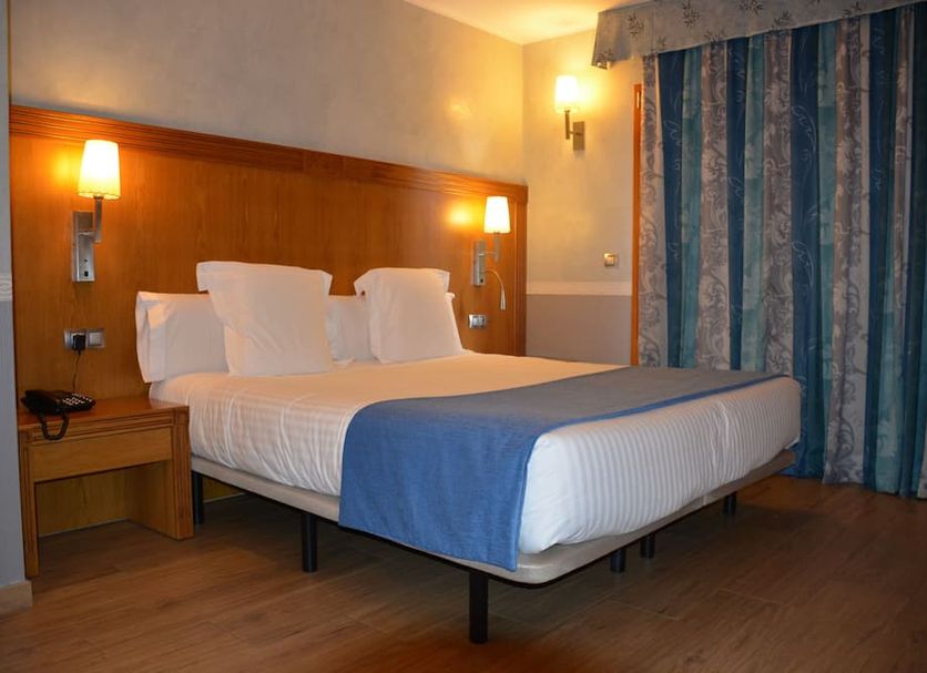 Hostal la Font guest room in Os de Civís with double bed, bedside lamps and striped curtains