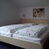 Pension Sonnalp in Ortisei, twin beds in a simple guest room with wall art and bedside lamps