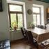 Homeplanet Hostel in Leipzig kitchen and dining area with wooden table, chairs, and large windows