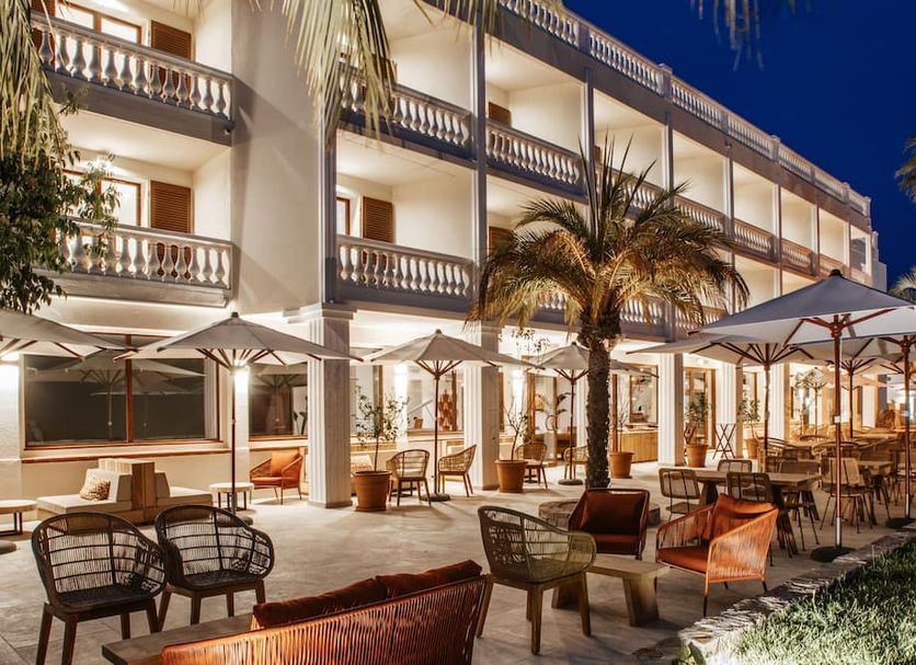 Le Mirage in Bormes-les-Mimosas features a lit outdoor terrace with tables, umbrellas and palm trees at night