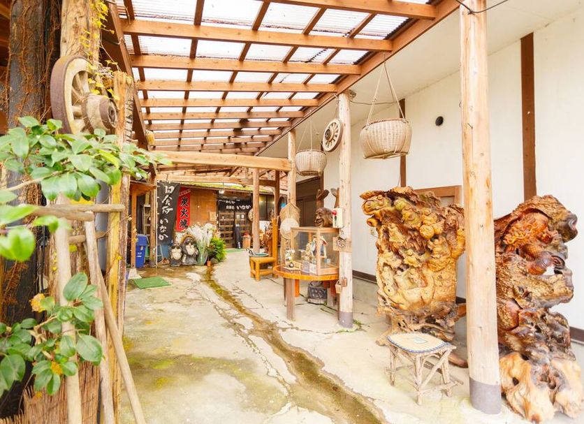 Yufuin Inakasou in Yufu features a covered rustic courtyard walkway with plants and wood accents.