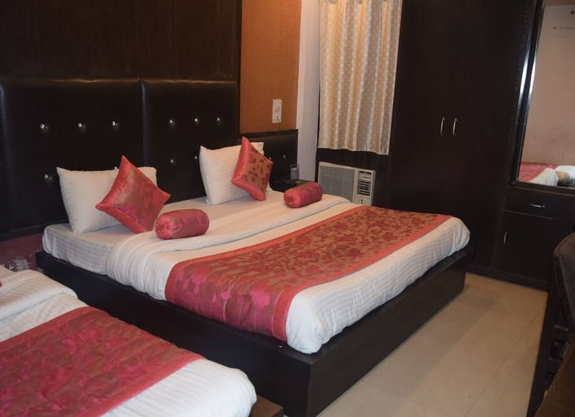 Hotel Trishul Haridwar guest room with two beds, dark wood wardrobe, and window air conditioner