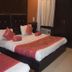 Hotel Trishul Haridwar guest room with two beds, dark wood wardrobe, and window air conditioner