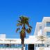Hotel Agaró in Chipiona with white facade, palm tree, and terrace umbrellas under a blue sky