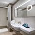 I Giardini di Cala Ginepro Hotel Resort bathroom with walk-in shower, sink, and illuminated mirror in Cala Liberotto