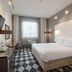 Qubus Hotel Bydgoszcz room with king bed, TV, desk and checkered floor in Bydgoszcz