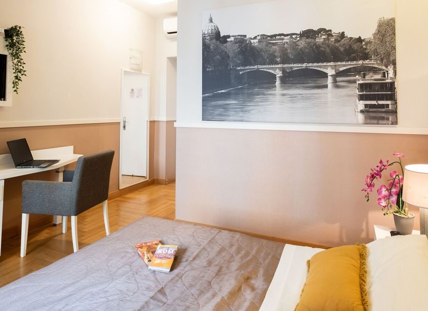 Rome River Inn room with bed, desk, wall art, and view of river bridge decor in Rome
