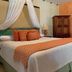 La Ermita de Santa Lucia in Antigua: a bed with canopy drapes, orange pillows, and wooden wardrobe.