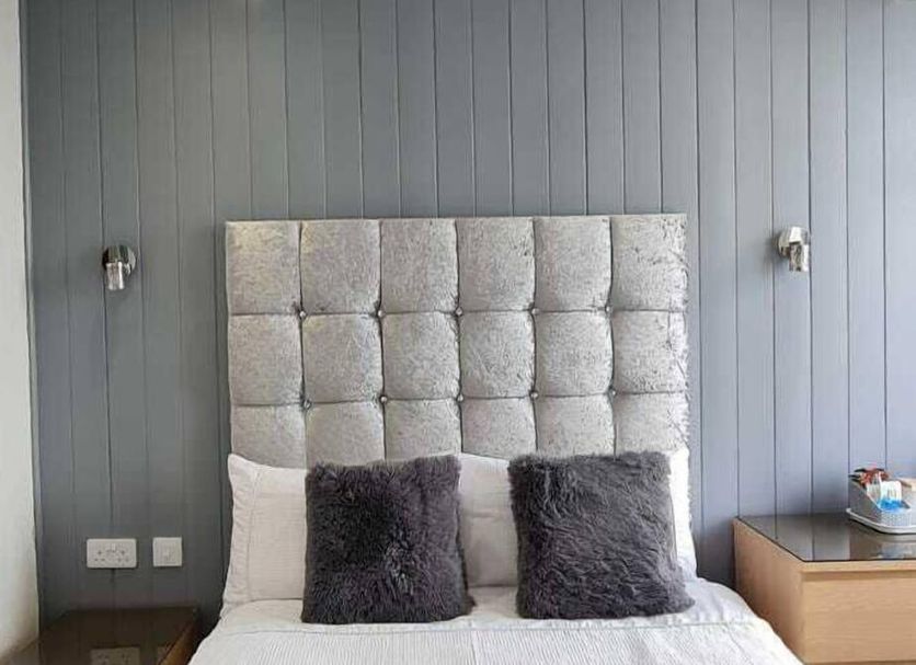 Ocean Bay, Blackpool bedroom with tufted headboard, gray paneled wall, and two dark accent pillows